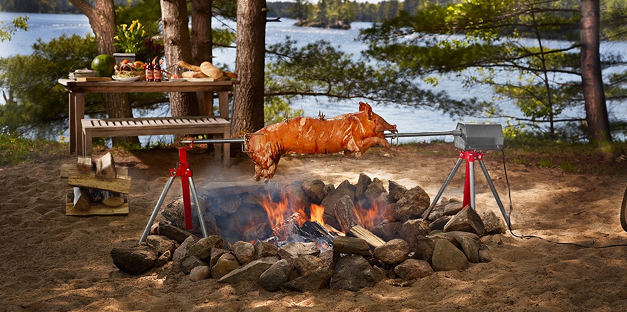 a pig is roasting on the baviator charcoal méchoui at a beautifull lake shore