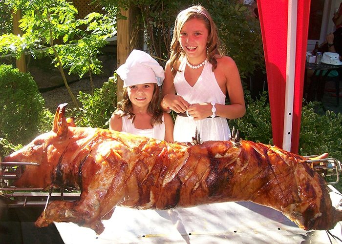 Wedding méchoui catering with mother and child looking at the finish pig roast
